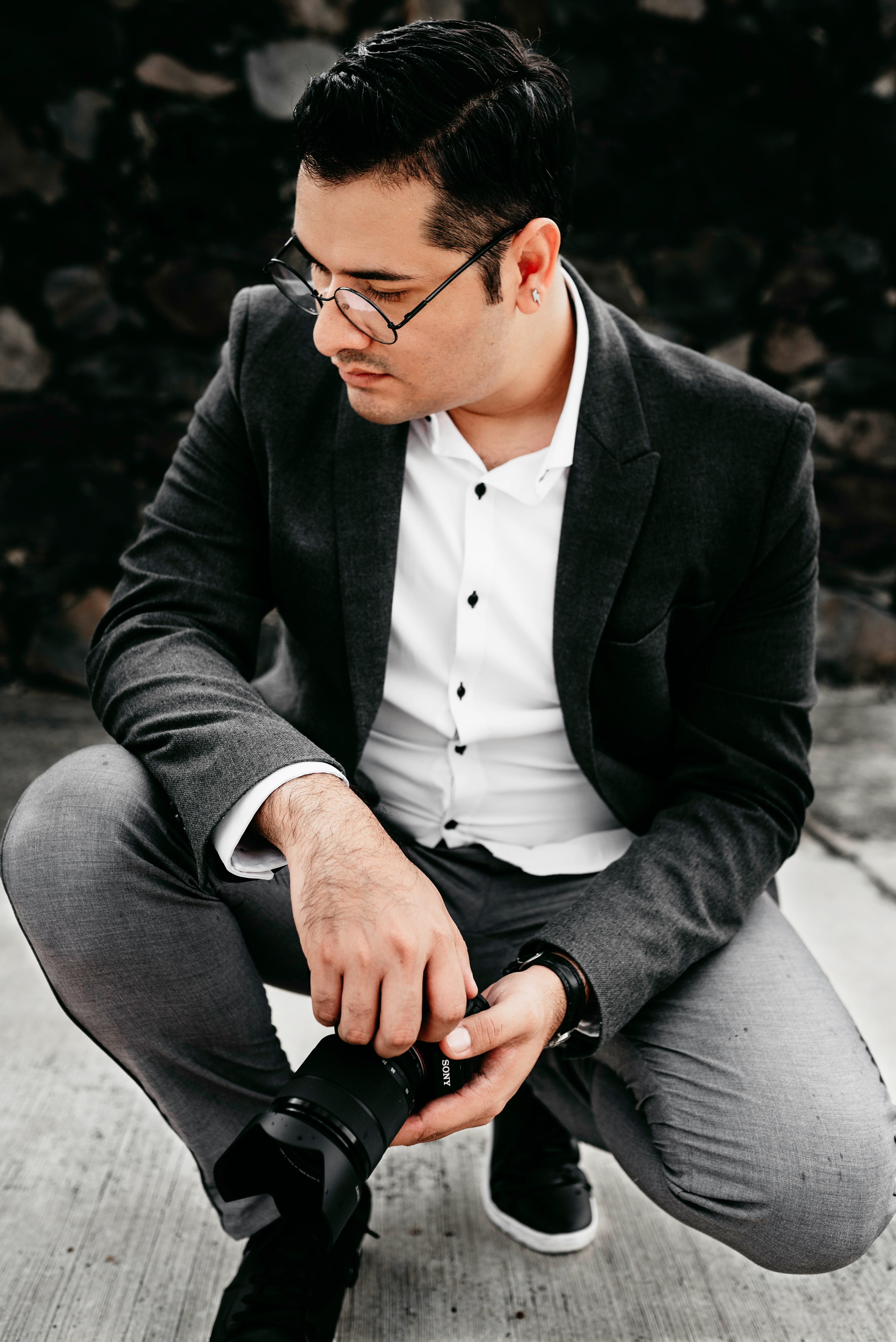 man in black suit jacket and gray dress pants sitting on gray concrete bench during daytime